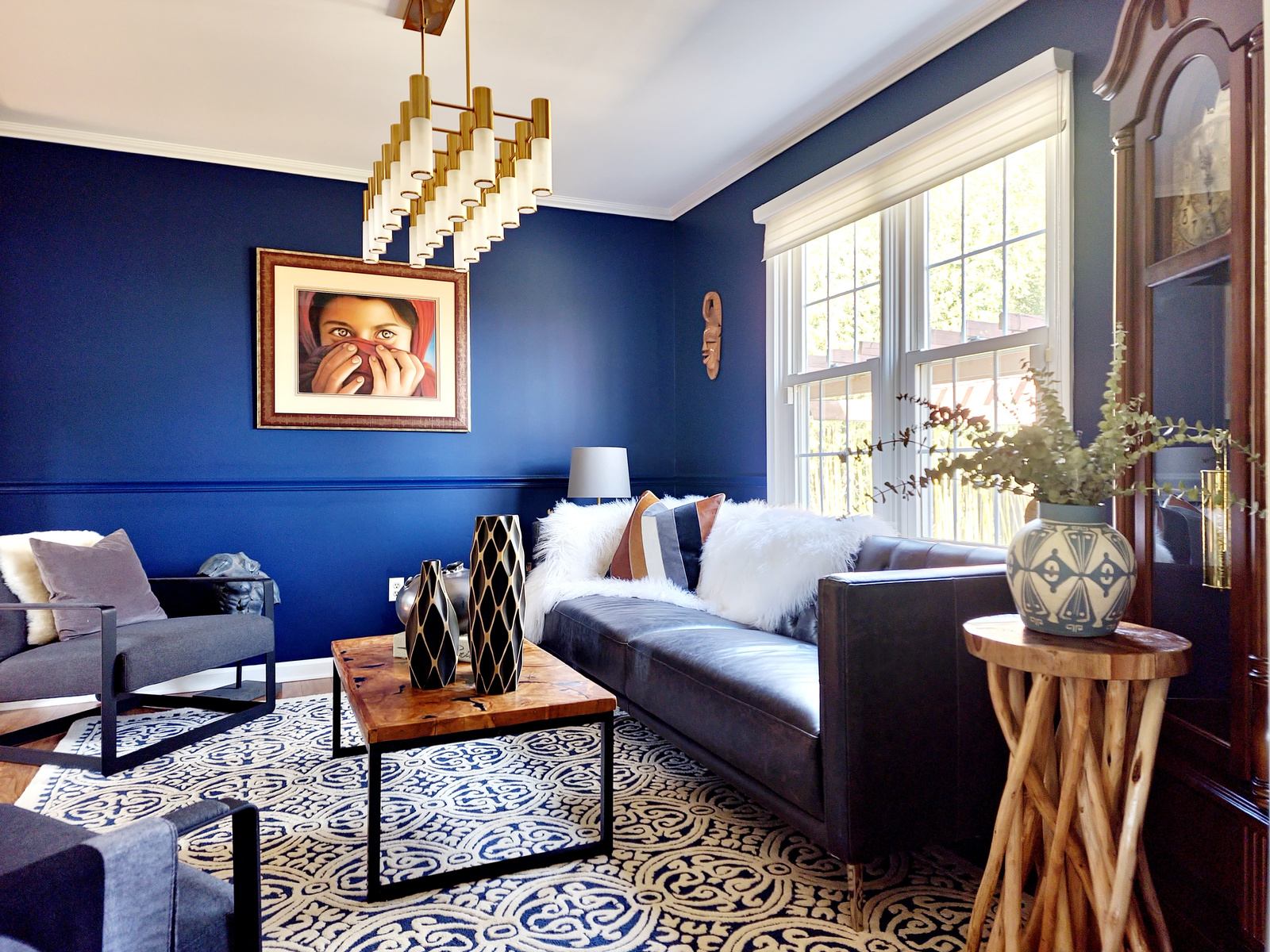 a living room with blue walls and a black and white patterned rug design by bespoke by ali fasi main line philadelpha